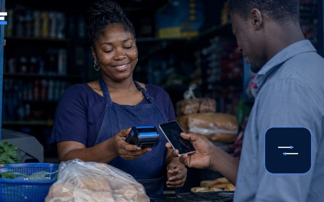 A Nigerian market customer completing a digital payment with a mobile phone