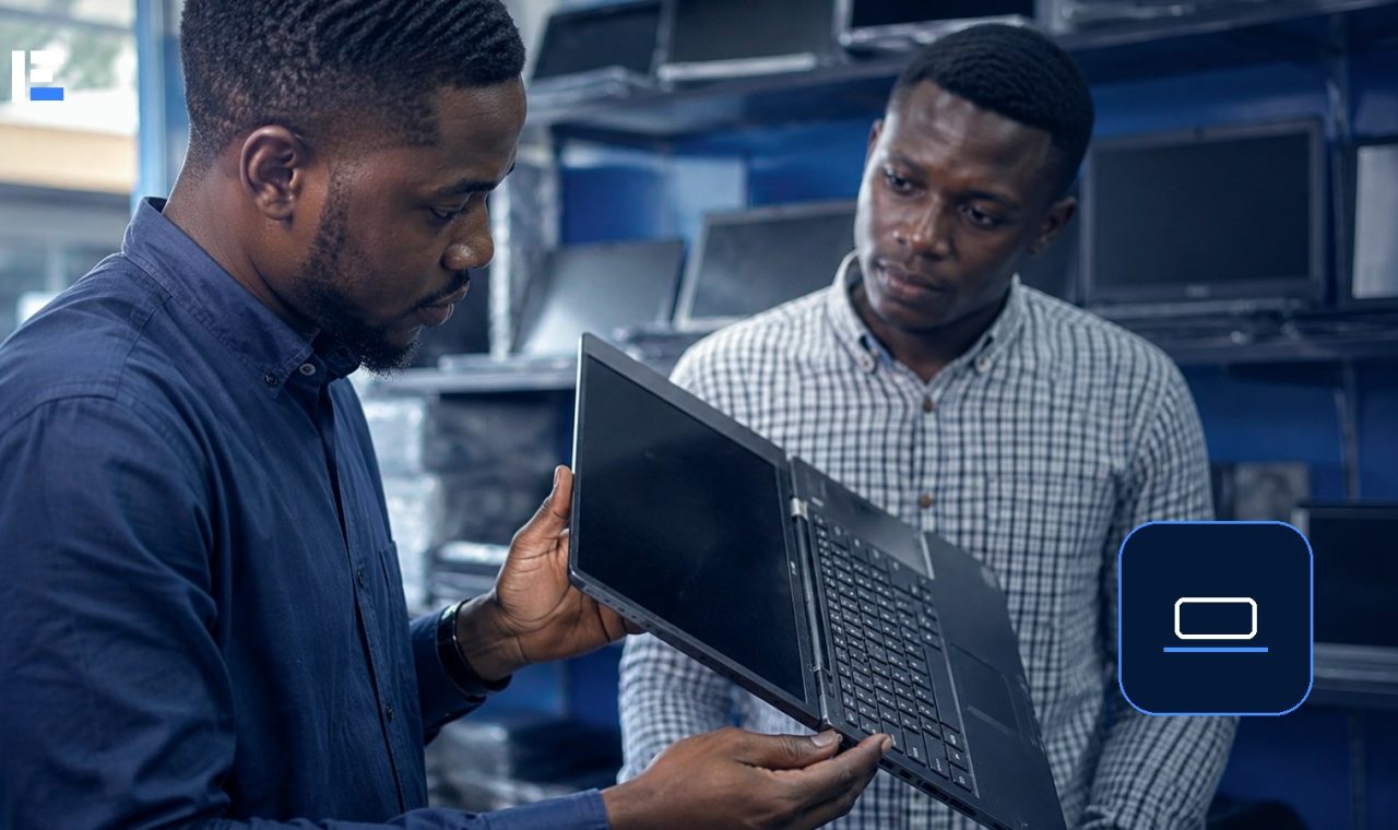Two Nigerian shoppers inspecting a used laptop in an electronics store